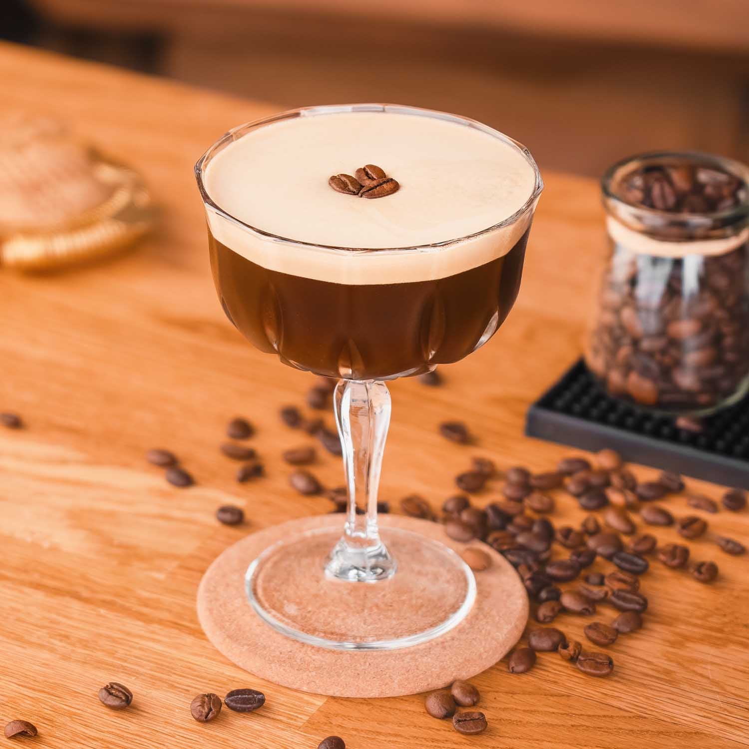 Butterscotch Golden Caramel Whiskey Likör Espresso Martini Cocktail, Espresso Martini im Glas, dekoriert mit Kaffeebohnen, Kaffeebohnen im Mittelgrund auf hellem Bar-Untergrund
