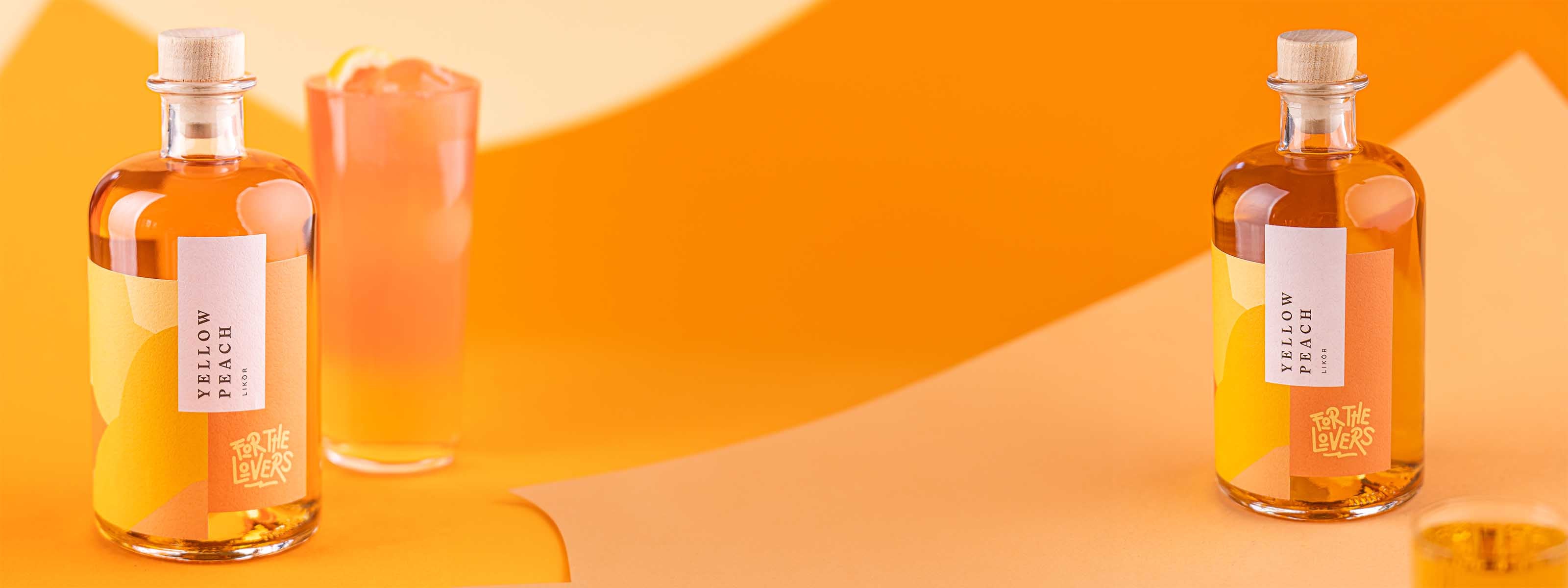 For the Lovers Yellow Peach Flaschen im Vordergrund, orangener Longdrink mit Grapefruit dekoriert im Mittelgrund auf gelb / orangenem Untergrund