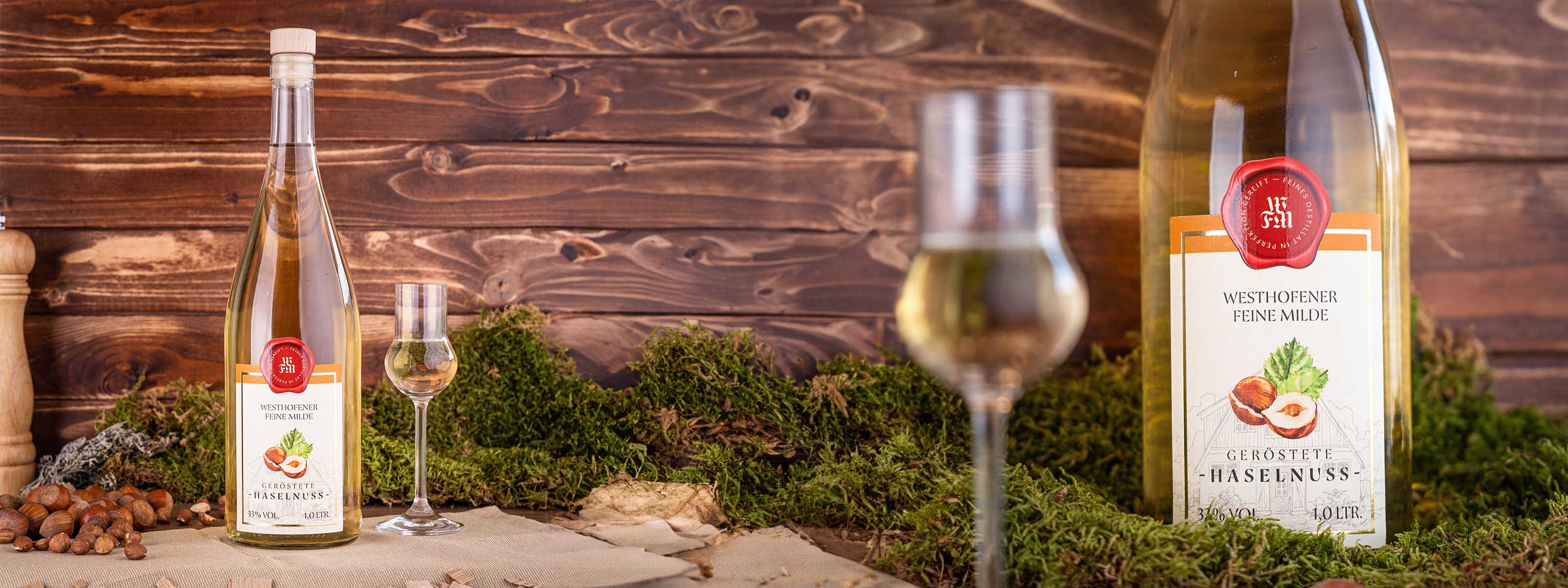 Westhofener Feine Milde Geröstete Haselnuss, Nosing-Glas unscharf im Vordergrund, Moos und Nüsse im Mittelgrund vor dunklen Holzlatten im Hintergrund