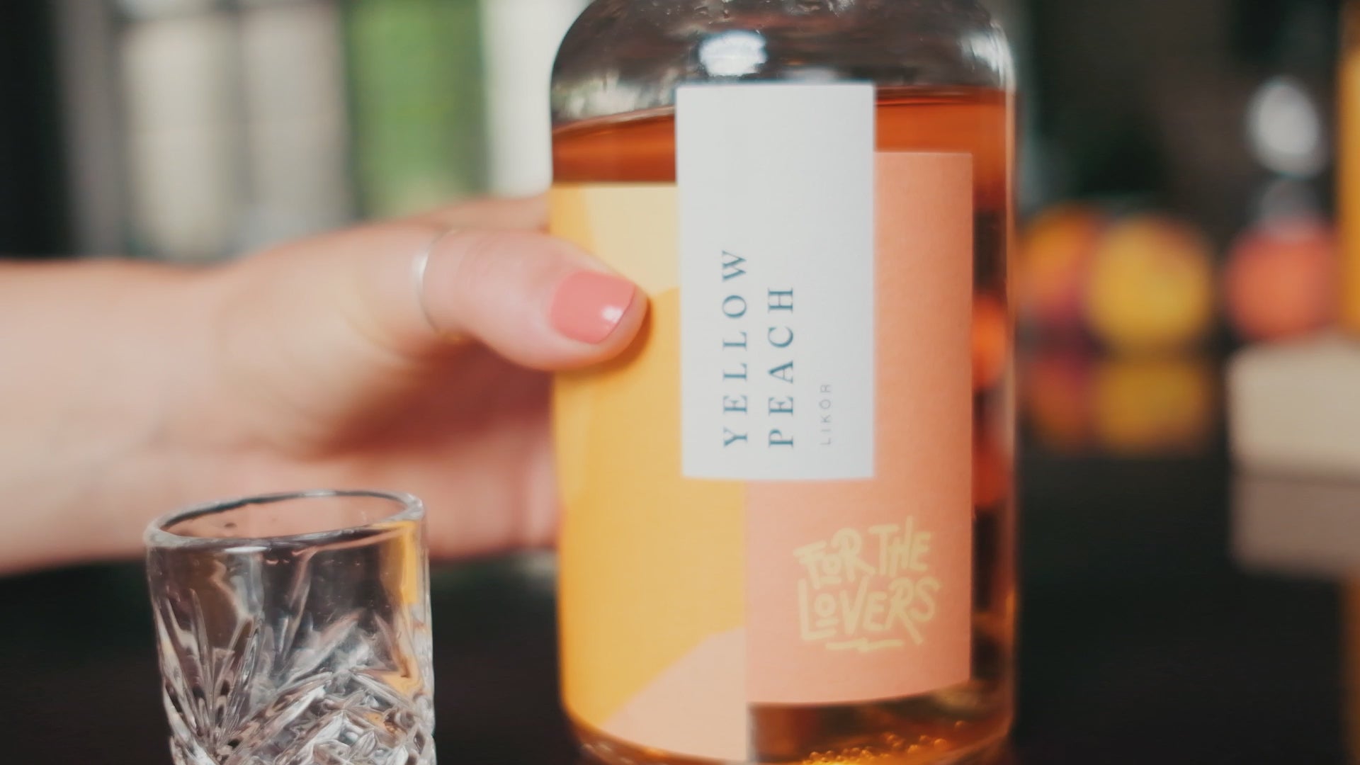 For the Lovers Yellow Peach, Likör wird in Shotglas eingeschenkt, Drink wird mit dem Finger gerührt, Flasche steht auf dem Bar-Tresen