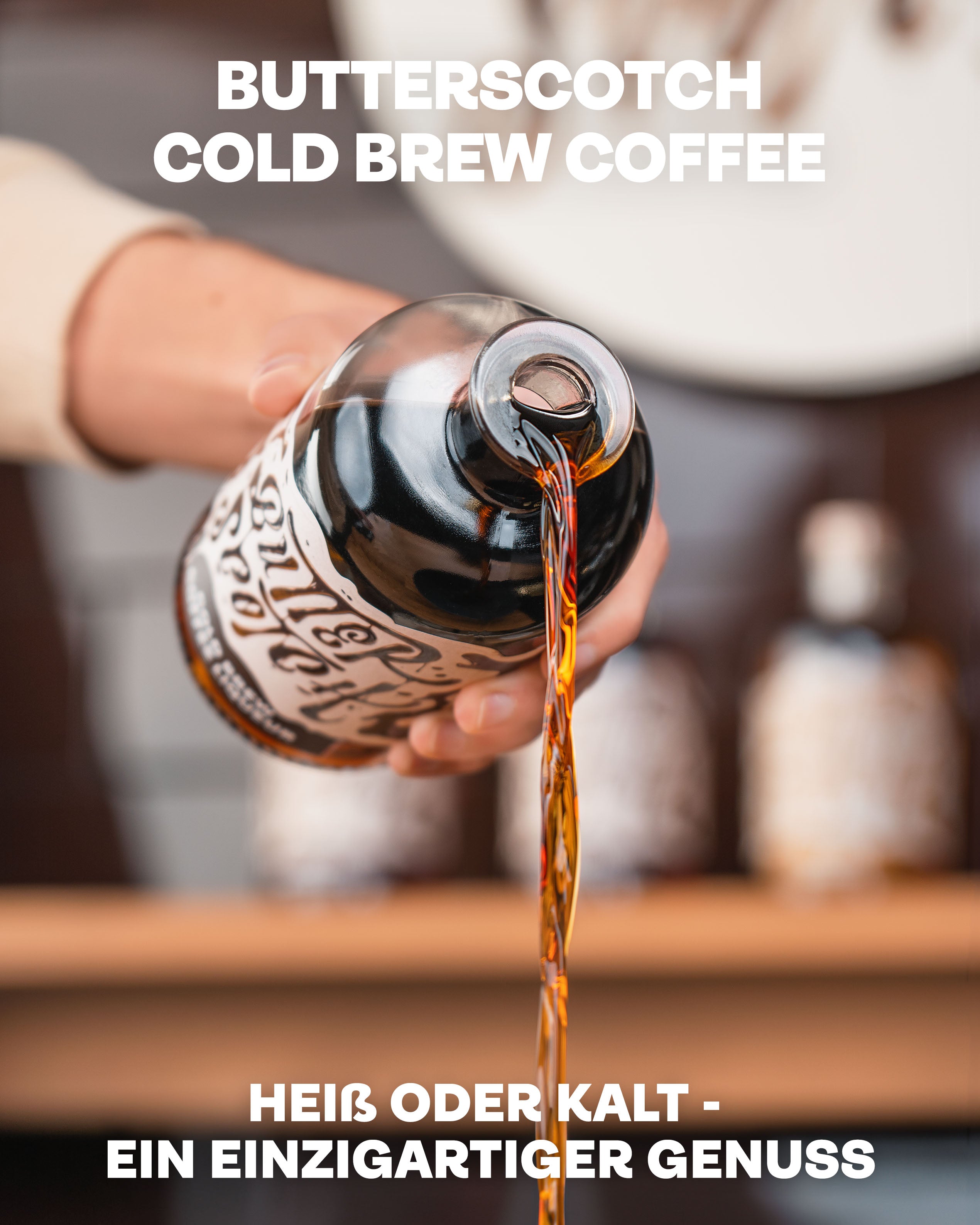 Butterscotch Coldbrew Coffee Likör, heiß oder kalt ein einzigartiger Genuss, Likör wird aus der Flasche ausgegossen vor Bar-Regal im Hintergrund
