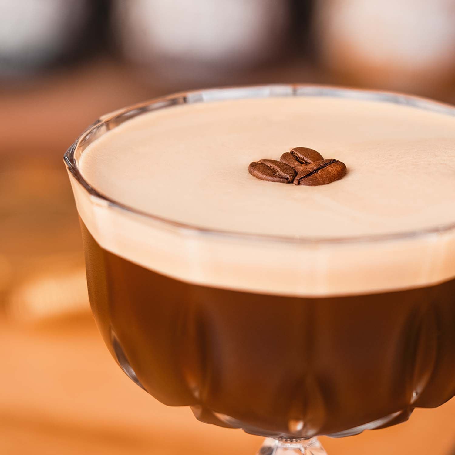 Butterscotch Espresso Martini, Detailaufnahme von einem Espresso Martini im Glas, dekoriert mit 3 Kaffeebohnen, vor hellem Hintergrundd