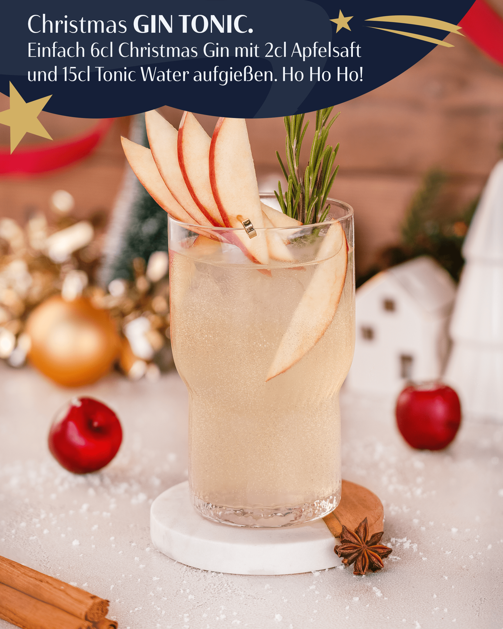 Christmas Gin & Tonic, 6cl Christmas Gin mit 2cl Apfelsaft und 15cl Tonic Water aufgießen. Gin Tonic vor weihnachtlich dekoriertem Hintergrund, dekoriert mit Apfelscheiben 