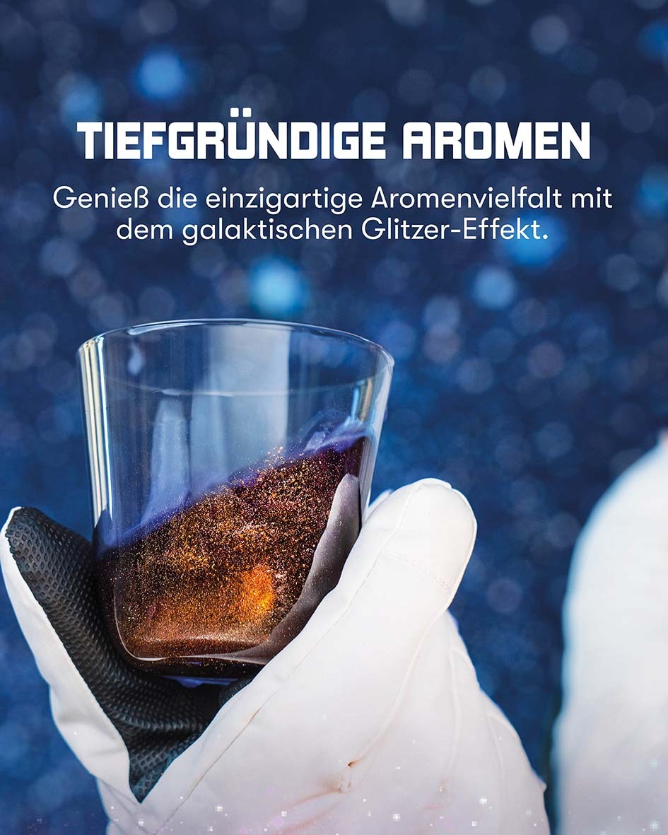 Tiefgründige Aromen - Genieße die einzigartige Aromenvielfalt mit dem galaktischen Glitzer-Effekt. Tiefblauer Glitzer Gin im Glas, gehalten von einem Astronauten, vor Sternenhimmel im Hintergrund