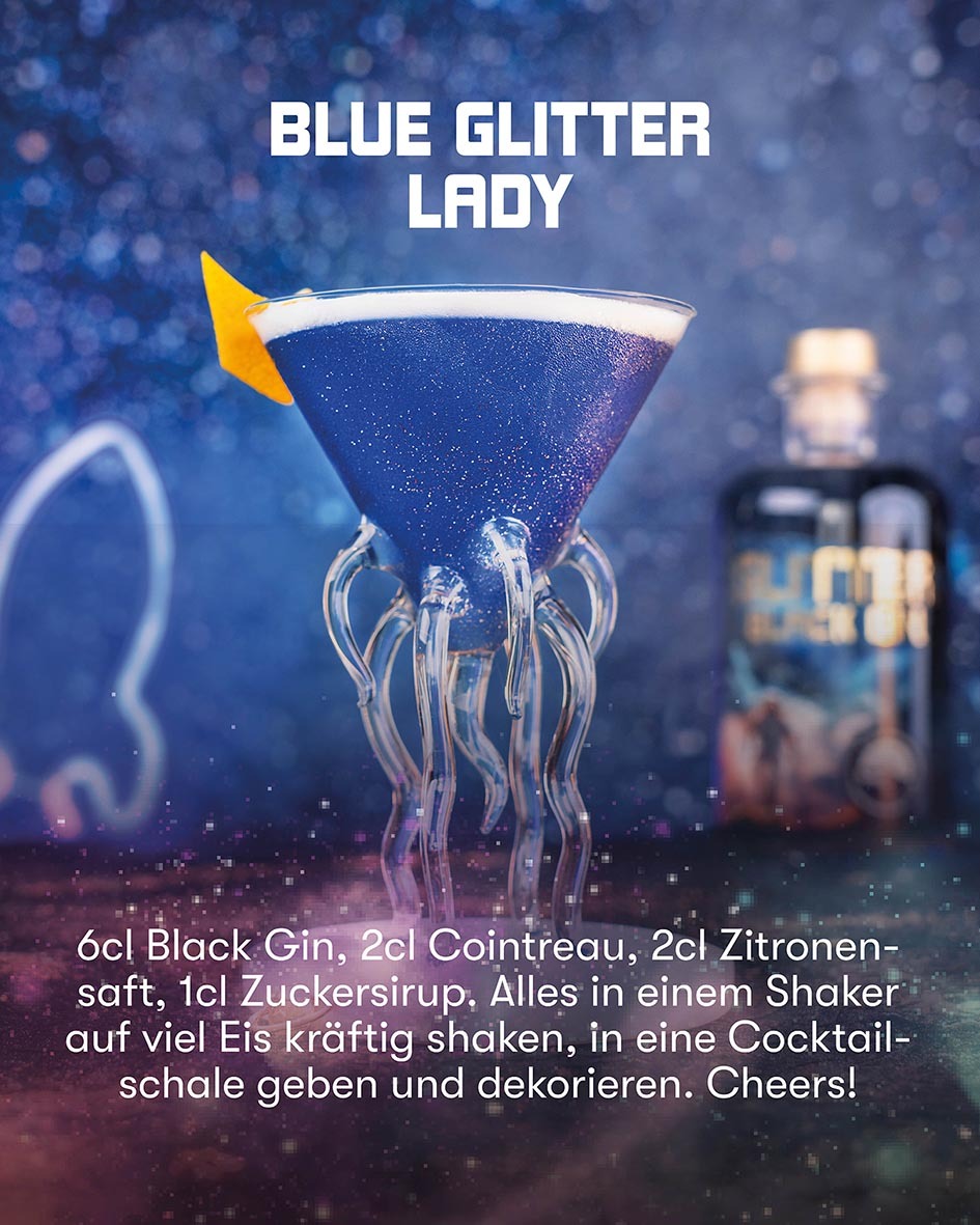 Blue Glitter Lady Cocktail, Glitter Black Gin Cocktail in einem besonderen Glas, dekoriert mit Zitronenzeste, vor Sternenhimmel und Flasche im Hintergrund