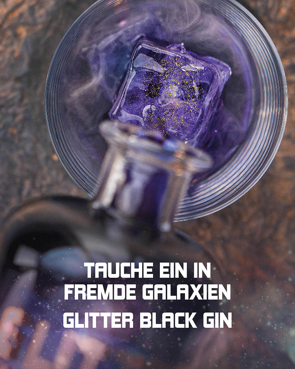 Tauche ein in fremde Galaxien, Glitter Black Gin wird von oben auf einen Eiswürfel in ein Glas gegossen