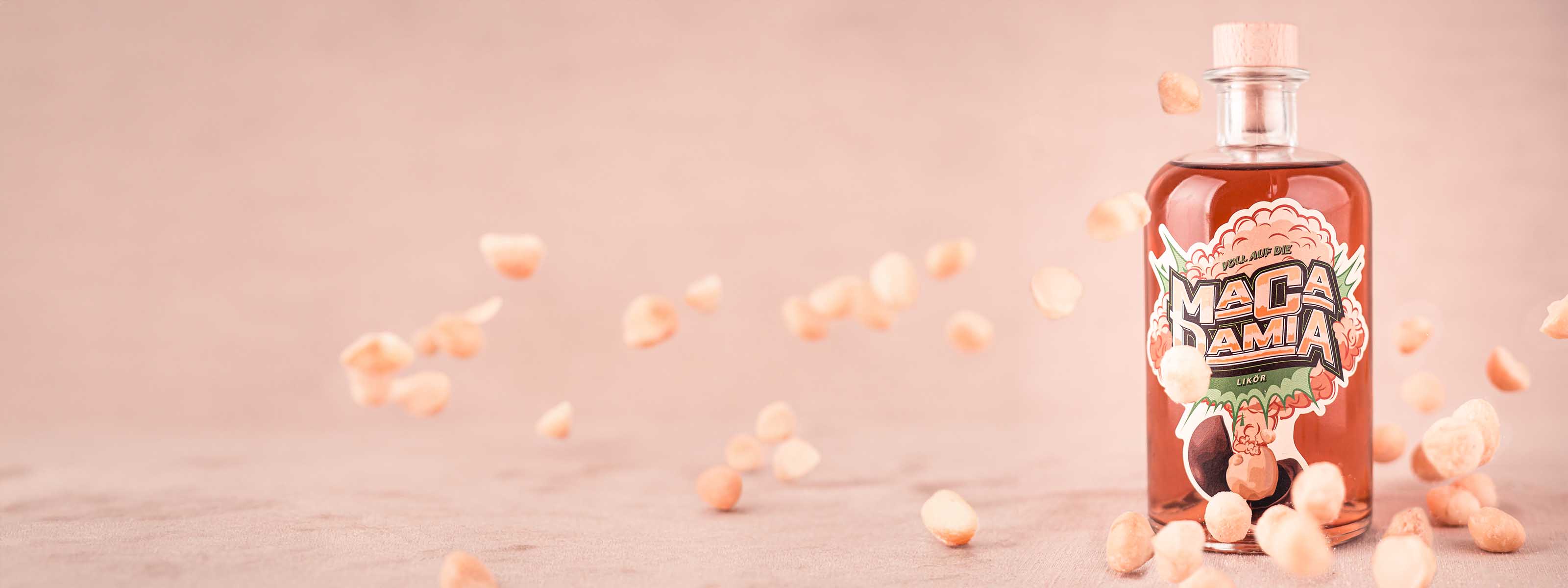 Flasche Hazellujah Macadamia Likör zwischen fallenden Macadamia Nüssen auf hellem Untergrund