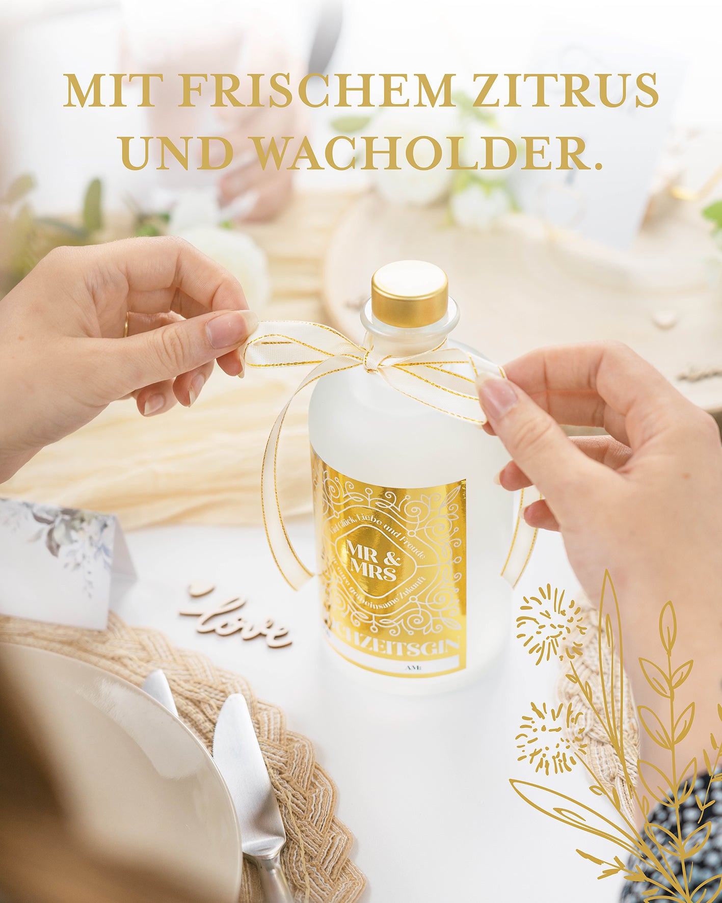 Ideales Hochzeitsgeschenk, individuell personalisierbar, Gold glänzendes Etikett, Flasche wird mit goldener Schleife dekoriert vor hochzeitlich dekoriertem Tisch