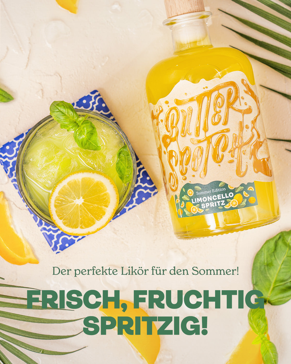 Der perfekte Likör für den Sommer - frisch, fruchtig, spritzig. Flasche liegend neben einem Basil Smash Cocktail von oben fotografiert, zwischen Minzblättern und Zitronen auf hellem Untergrund platziert